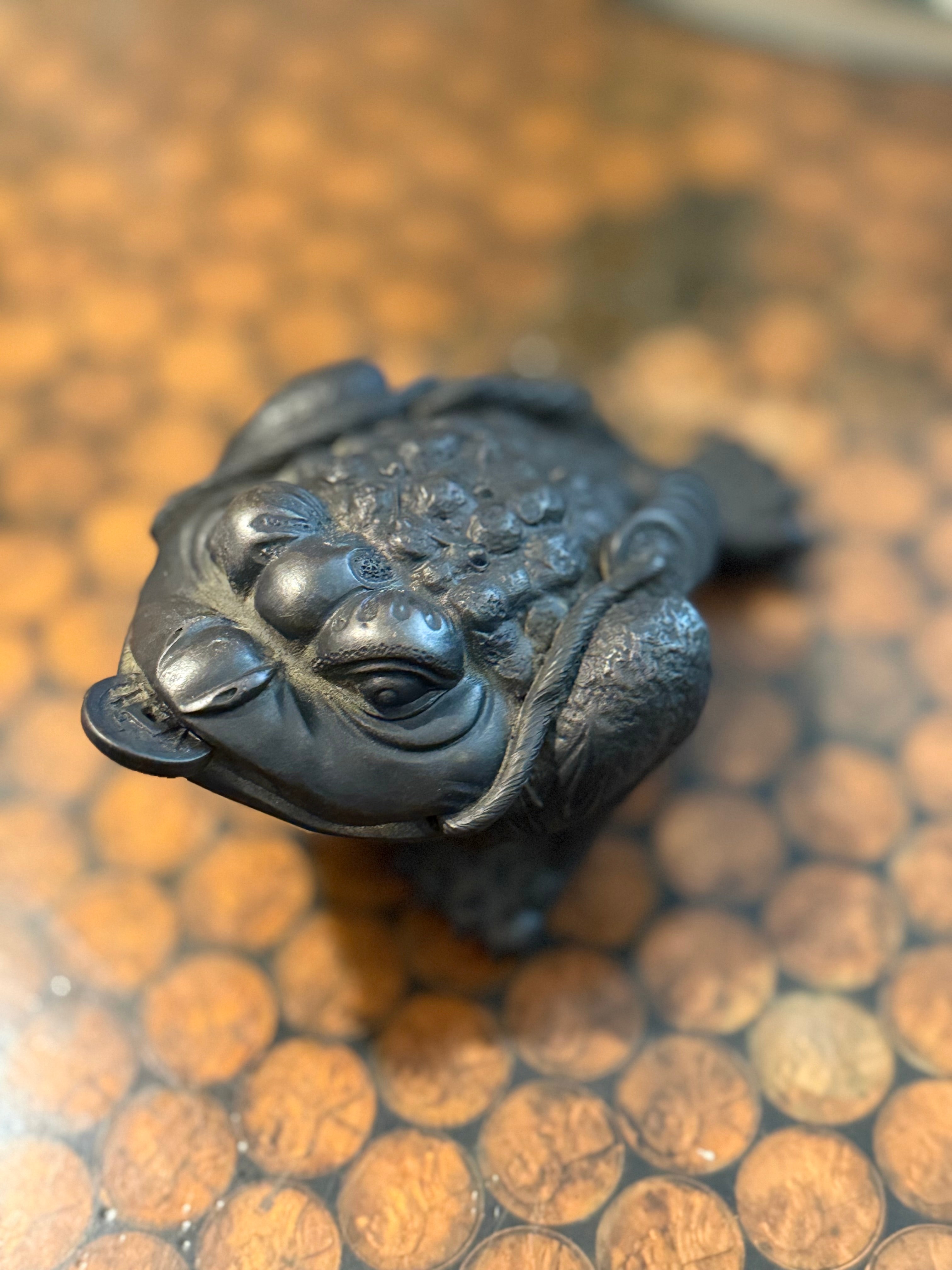 Black frog thing with coin in mouth